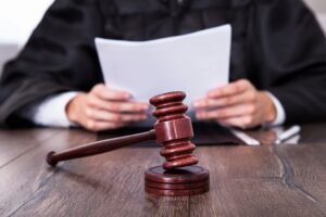 Judge holding legal documents with a wooden gavel on the table