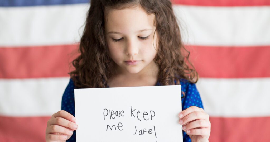 Young girl holding a sign that reads "Please keep me safe," highlighting concerns over child safety and gun violence