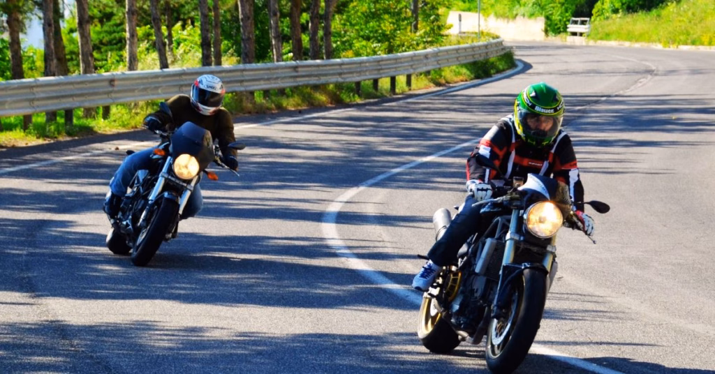 Two motorcyclists wearing helmets and safety gear riding cautiously on a curved road, promoting safe riding practices during Motorcycle Safety Awareness Month in Kansas City