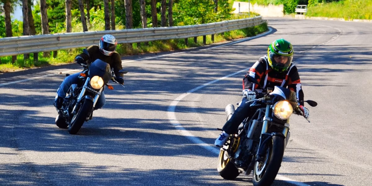 Motorcycle Safety Awareness Month - Kendall Law Group Kansas City Motorcycle Accident Injury Lawyers Two motorcyclists wearing helmets and safety gear riding cautiously on a curved road, promoting safe riding practices during Motorcycle Safety Awareness Month in Kansas City