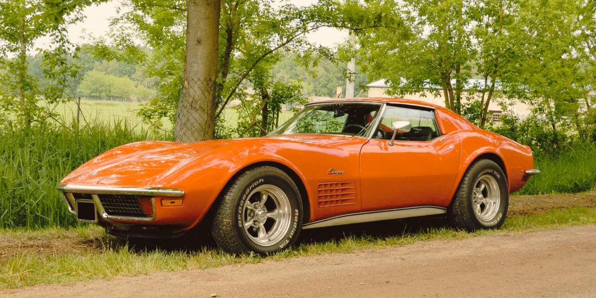 kansas-city-car-accident-property-damage-claim Red classic Chevrolet Corvette parked near trees, representing a collector vehicle that could be involved in a Kansas City auto accident property damage claim.